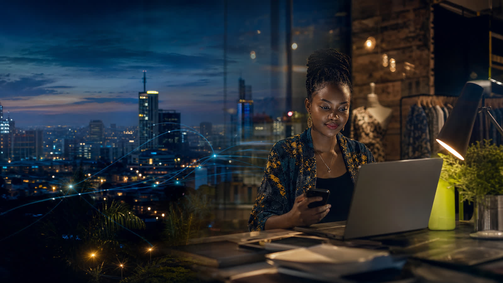 Business owner working late at a laptop above a lit city skyline